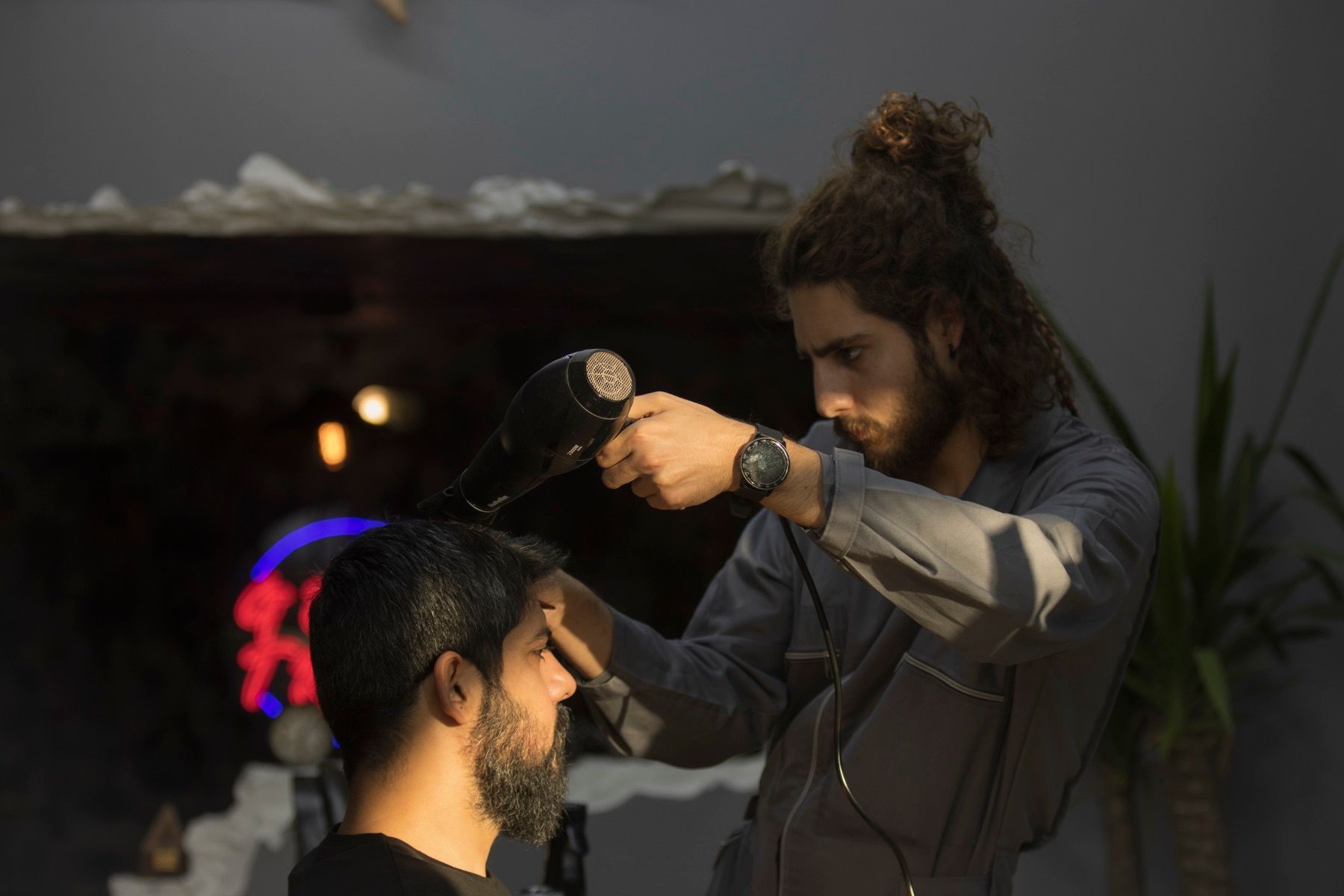 Kapper föhnt het haar van een klant in een schemerige salon
