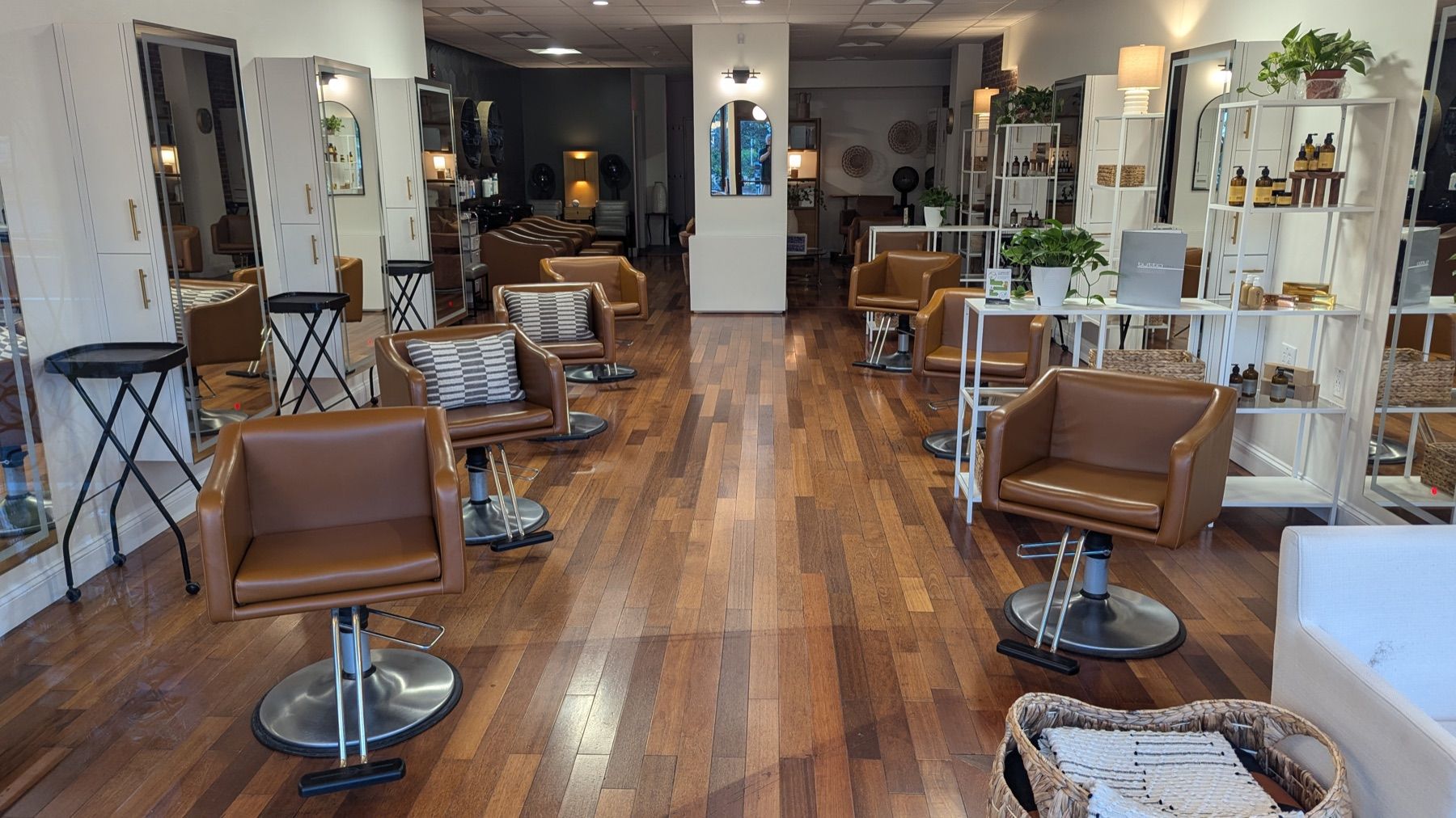 De salon met bruinleren stoelen, spiegels en een houten vloer