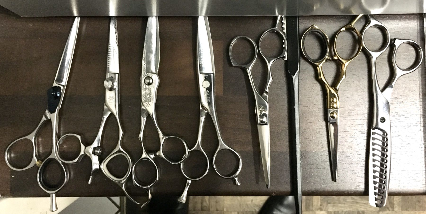 Een rij professionele kappersscharen op een donkere ondergrond